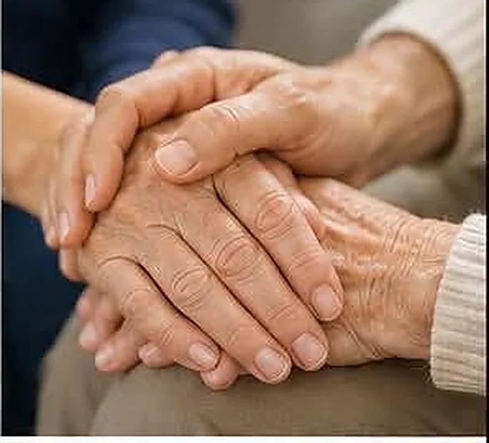 A younger pair of hands gently holding an older pair of hands
