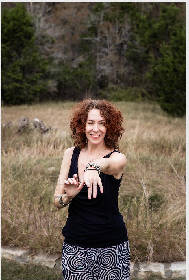 The practitioner demonstrating EFT tapping on the side of the hand in an open meadow